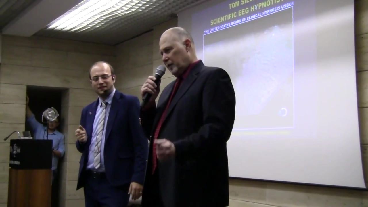 Tom Silver al Congresso Mondiale di Ipnosi di Roma nel 2017, davanti alla slide della sua conferenza sull'ipnosi scientifica con EEG